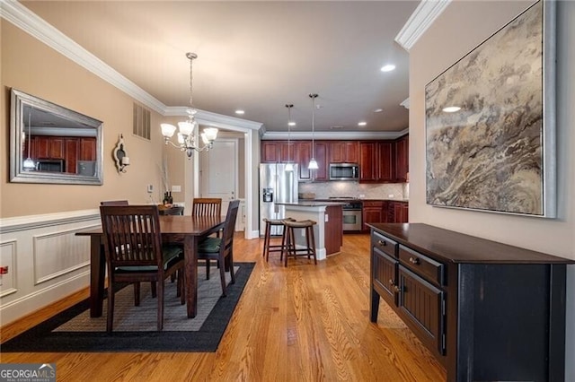 dining space featuring light hardwood / wood-style floors, ornamental molding, and a chandelier