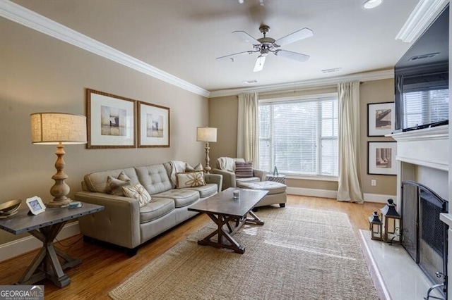 living room featuring ceiling fan, ornamental molding, and light wood-type flooring