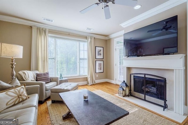 living room featuring crown molding, light wood-type flooring, and ceiling fan