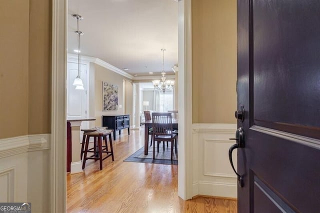 foyer entrance with ornamental molding, a notable chandelier, and light hardwood / wood-style floors