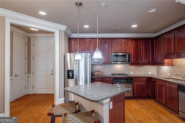 kitchen featuring pendant lighting, light hardwood / wood-style flooring, a kitchen bar, and stainless steel appliances