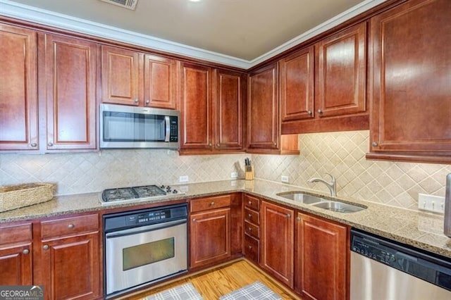 kitchen with decorative backsplash, appliances with stainless steel finishes, light stone countertops, light hardwood / wood-style floors, and sink