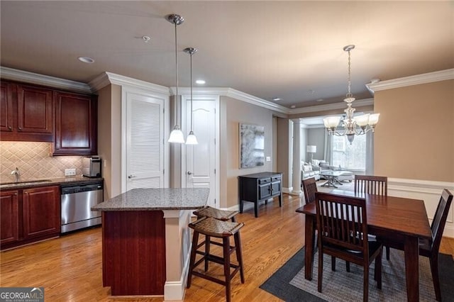 dining area featuring sink, ornamental molding, light hardwood / wood-style flooring, and a chandelier