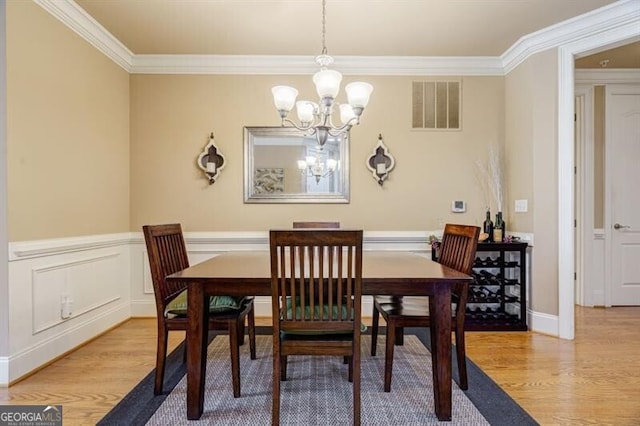 dining space featuring crown molding, light hardwood / wood-style flooring, and a notable chandelier