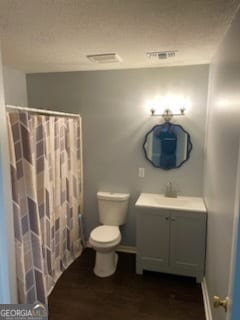 bathroom featuring vanity, a textured ceiling, hardwood / wood-style flooring, and toilet