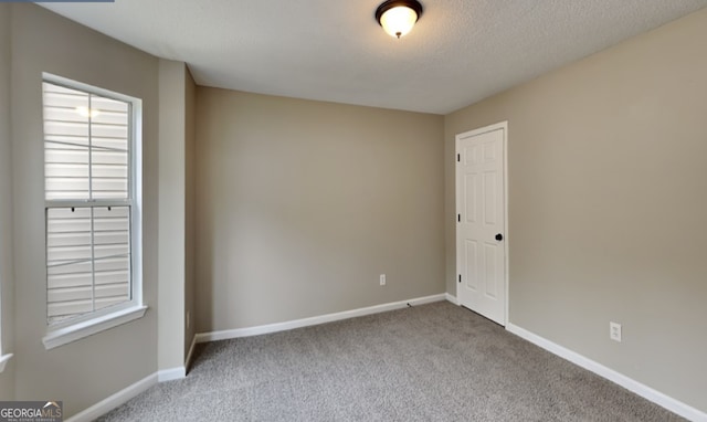 unfurnished room featuring a textured ceiling and light colored carpet