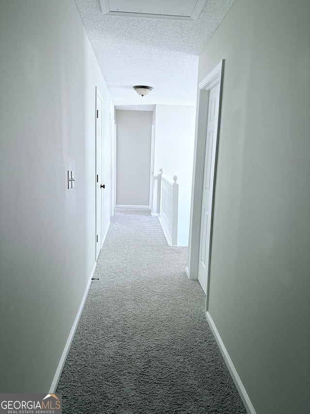 corridor featuring a textured ceiling and carpet