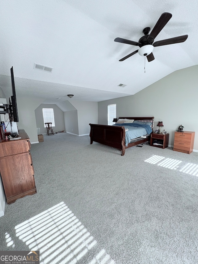 bedroom featuring ceiling fan, a textured ceiling, vaulted ceiling, and light colored carpet