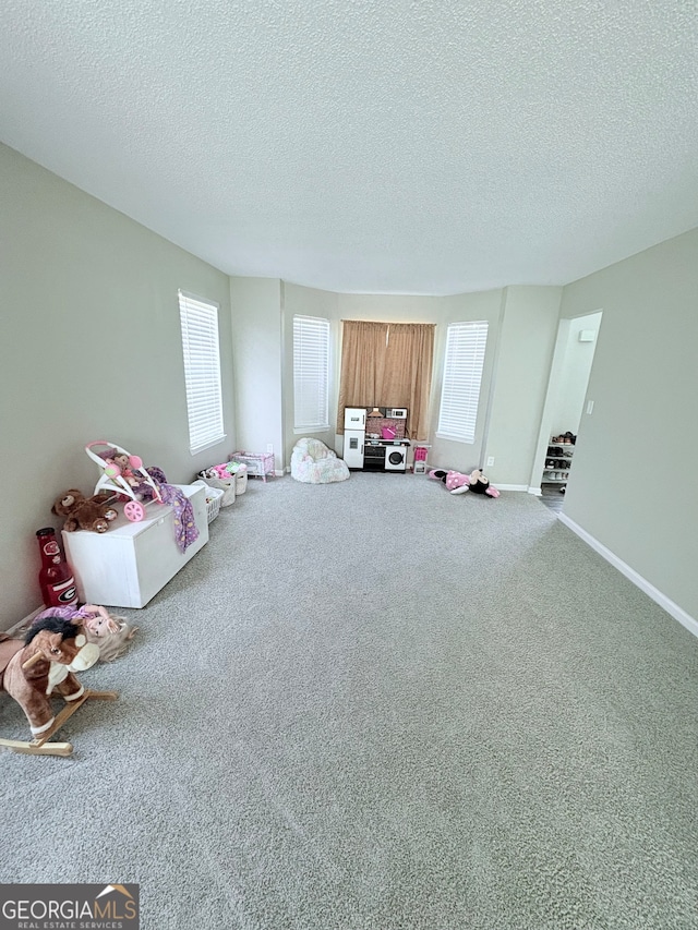 playroom with a textured ceiling, carpet flooring, and a wealth of natural light