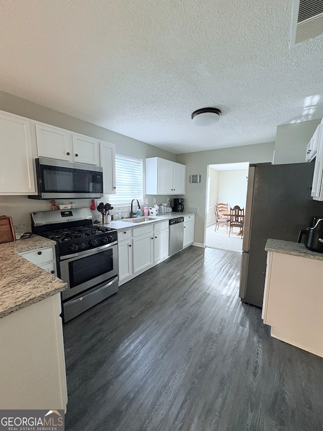 kitchen with dark hardwood / wood-style floors, sink, white cabinets, appliances with stainless steel finishes, and a textured ceiling