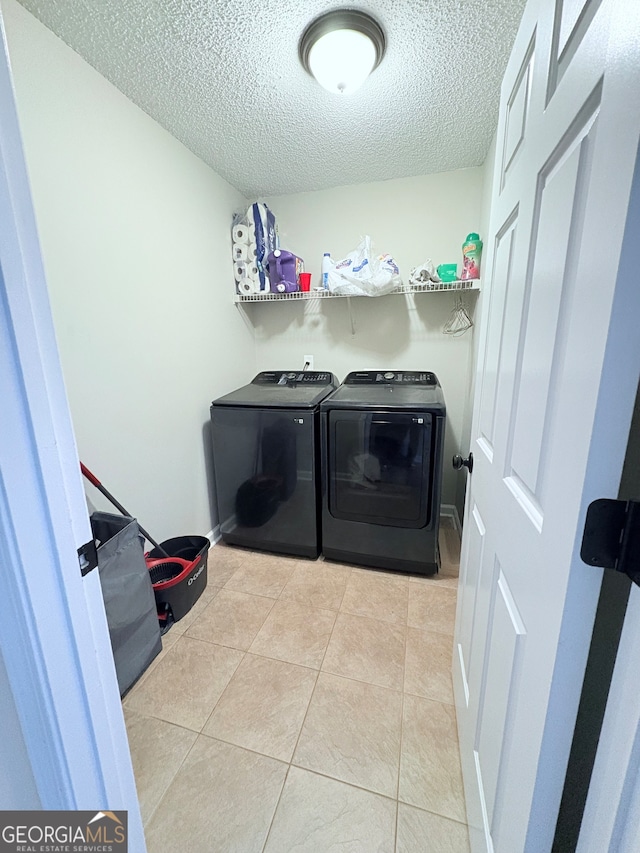 laundry area featuring washer and dryer, a textured ceiling, and light tile patterned floors