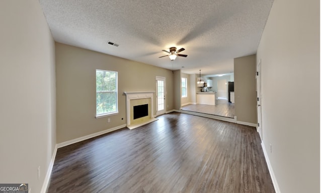 unfurnished living room with dark wood-type flooring, ceiling fan, and a textured ceiling