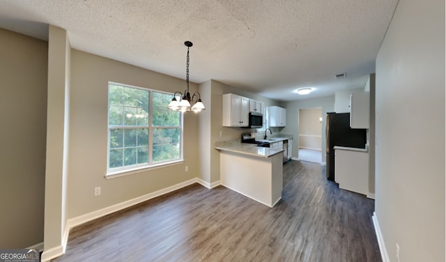 kitchen with a textured ceiling, kitchen peninsula, white cabinetry, stainless steel appliances, and dark wood-type flooring