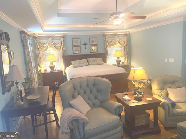 bedroom with hardwood / wood-style floors, crown molding, a raised ceiling, and ceiling fan