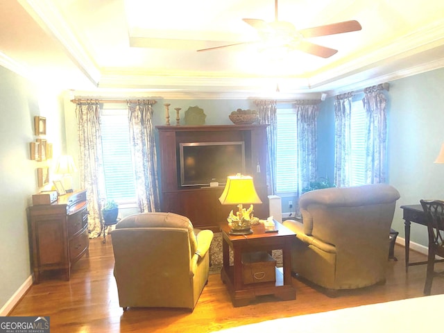 living area with hardwood / wood-style flooring, a healthy amount of sunlight, a tray ceiling, and crown molding