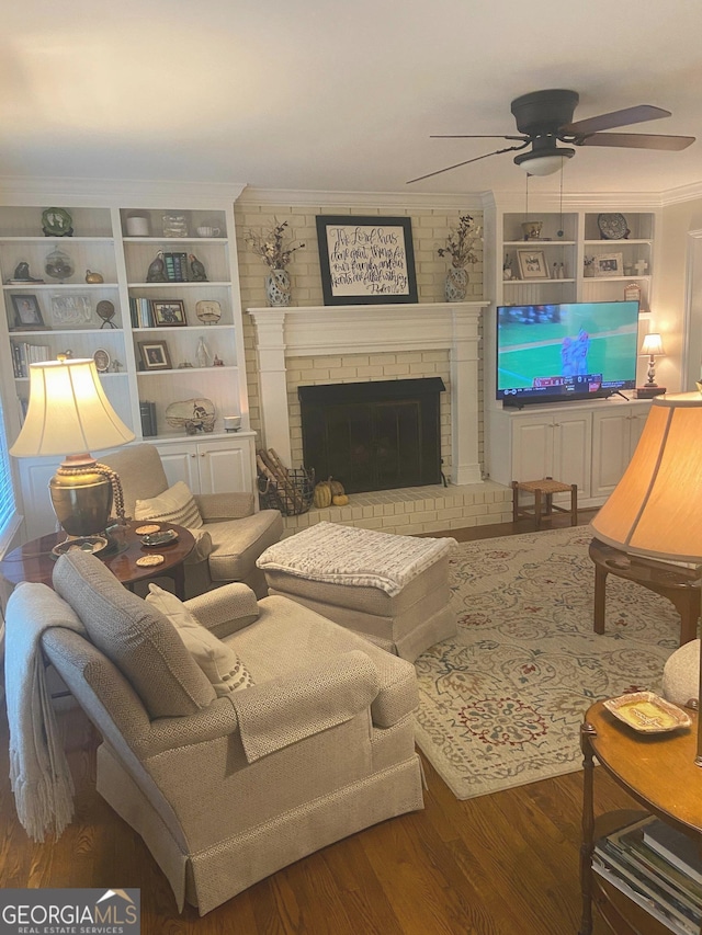 living room with crown molding, a brick fireplace, hardwood / wood-style flooring, and ceiling fan