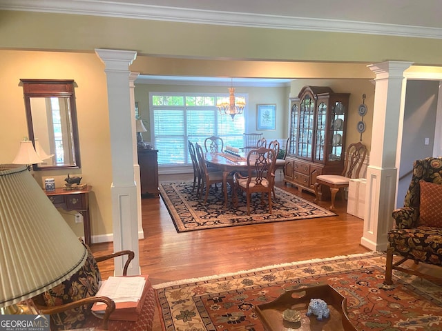 dining area with ornate columns, ornamental molding, hardwood / wood-style flooring, and a chandelier