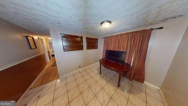 hall featuring light tile patterned flooring and a textured ceiling