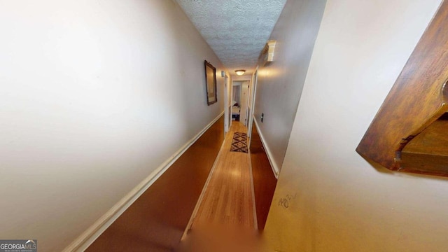 hall featuring wood-type flooring and a textured ceiling