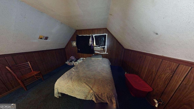 bedroom featuring lofted ceiling, wood walls, and a textured ceiling