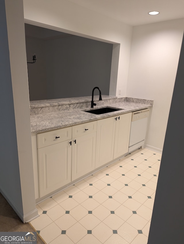 kitchen with dishwasher, light stone countertops, and sink