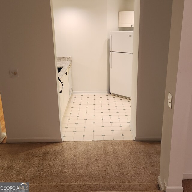 kitchen featuring white cabinets, white refrigerator, and light carpet