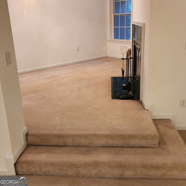 unfurnished living room with carpet floors and a fireplace