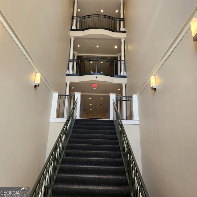 staircase featuring decorative columns and a towering ceiling