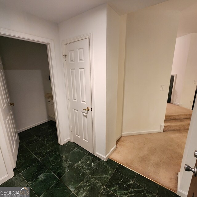 hallway featuring dark colored carpet