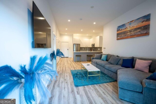 living room with light hardwood / wood-style flooring and sink