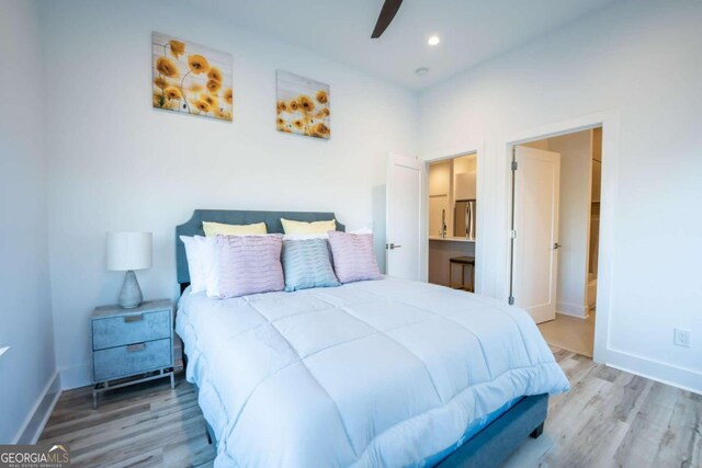 bedroom featuring light hardwood / wood-style flooring, ensuite bathroom, and ceiling fan