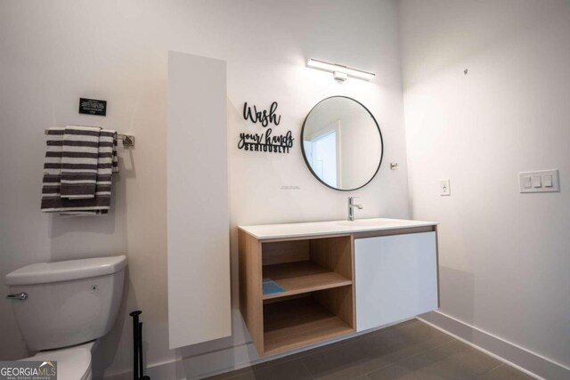 bathroom with toilet, vanity, and tile patterned flooring