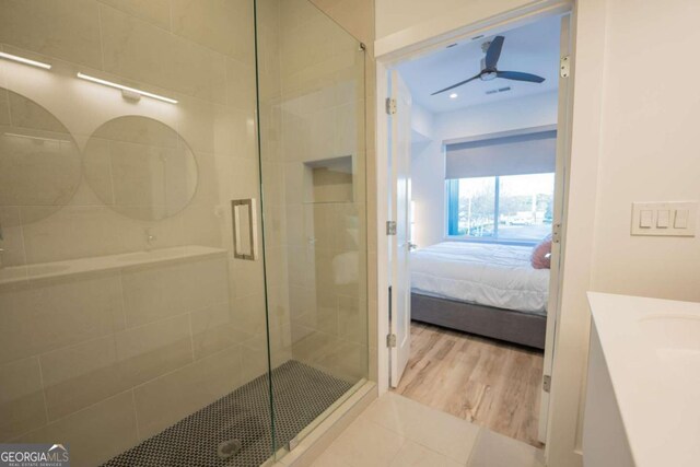 bathroom with vanity, hardwood / wood-style flooring, a shower with shower door, and ceiling fan