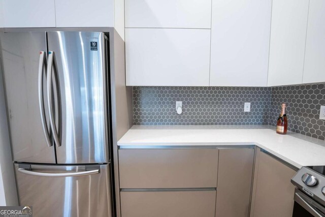 kitchen featuring white cabinetry, backsplash, and stainless steel refrigerator