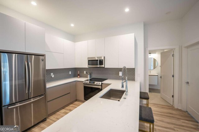 kitchen with sink, white cabinetry, light hardwood / wood-style flooring, and stainless steel appliances