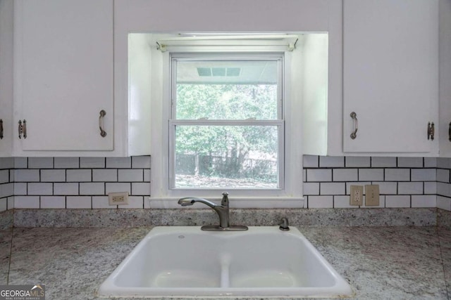 kitchen featuring white cabinetry, tasteful backsplash, sink, and light stone counters