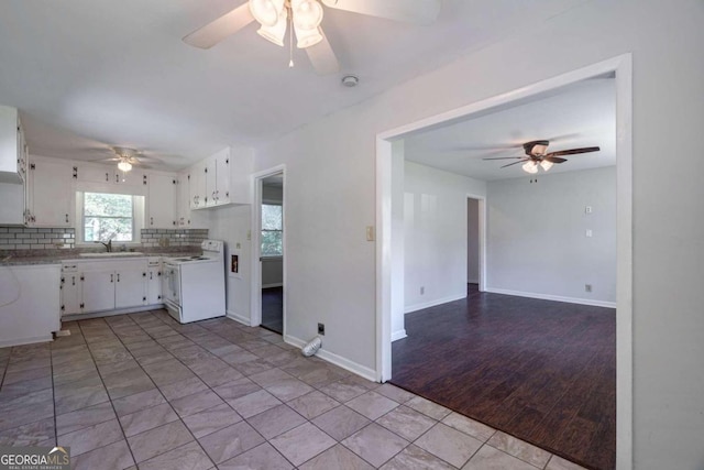 kitchen featuring tasteful backsplash, sink, white electric stove, white cabinetry, and light hardwood / wood-style flooring