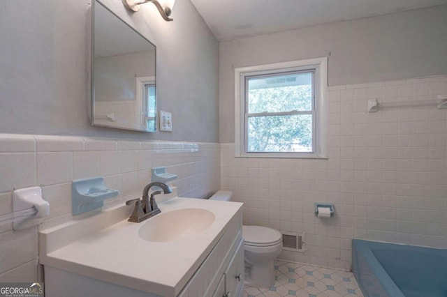 bathroom featuring tile walls, toilet, vanity, a tub to relax in, and tile patterned flooring