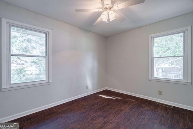 spare room with dark wood-type flooring, ceiling fan, and plenty of natural light