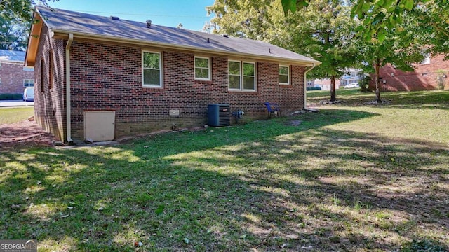 rear view of property featuring central AC and a yard