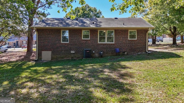 rear view of property featuring a lawn and cooling unit