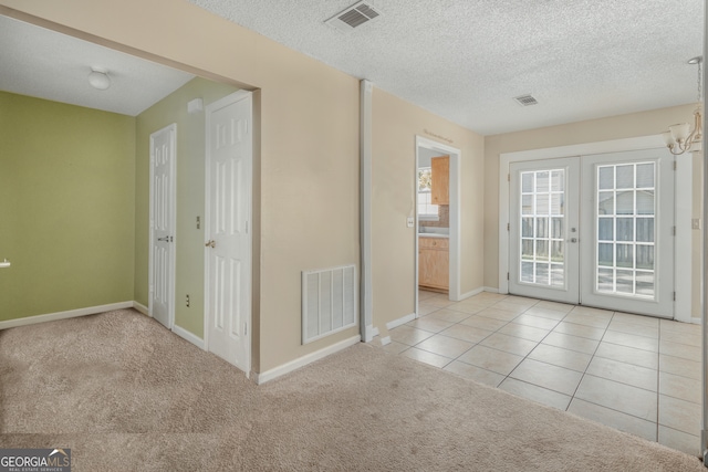 carpeted spare room with french doors and a textured ceiling