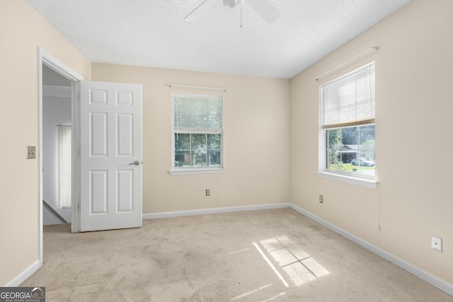 carpeted spare room featuring ceiling fan and a textured ceiling