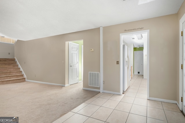 hall with a textured ceiling and light colored carpet