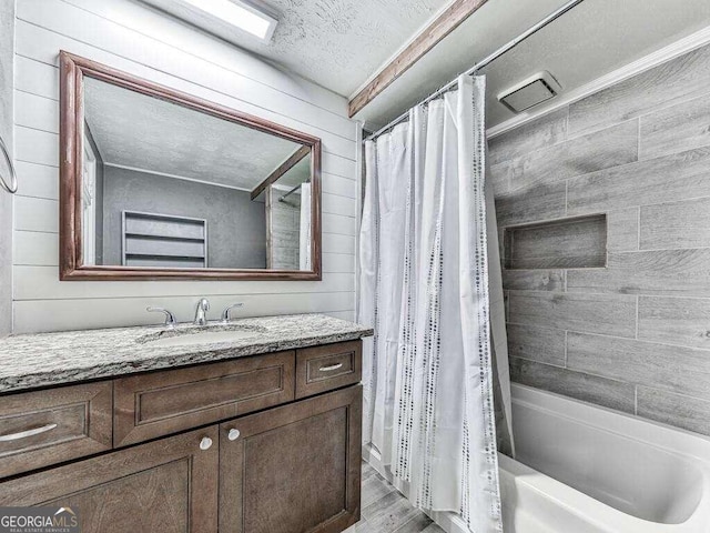 bathroom featuring a textured ceiling, shower / bathtub combination with curtain, wood-type flooring, wood walls, and vanity