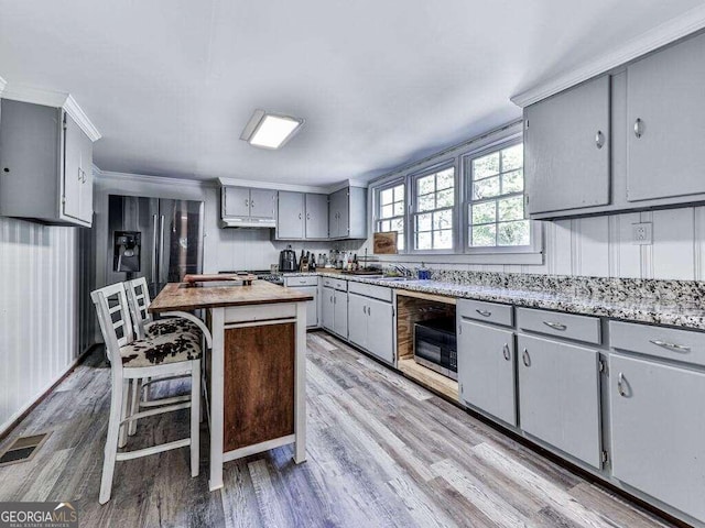 kitchen featuring gray cabinets, ornamental molding, a kitchen island, and light wood-type flooring