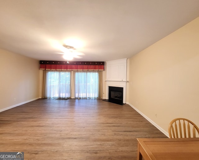 unfurnished living room with ceiling fan, wood-type flooring, and a large fireplace