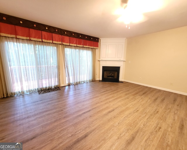 unfurnished living room featuring hardwood / wood-style flooring, a fireplace, and ceiling fan