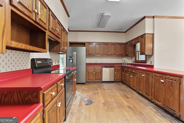 kitchen with sink, stainless steel appliances, light hardwood / wood-style flooring, a textured ceiling, and ornamental molding