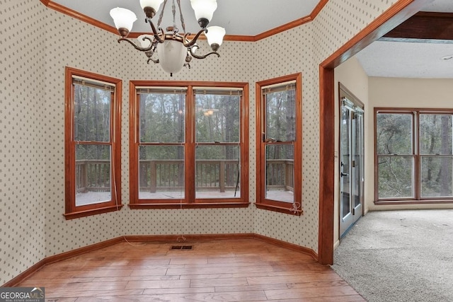 unfurnished dining area featuring ornamental molding, carpet floors, and an inviting chandelier